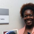 Clinics should be safe spaces; woman stands next to patient safety wall sign